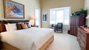 A bedroom with a large bed, a wooden dresser, a chair, and a desk. - JHRL - Pieper Garden Home 30 night rental (Wilson)
