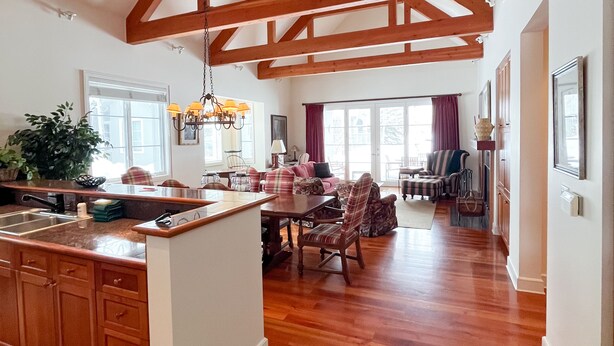 A spacious kitchen with wooden beams, a dining area with a table and chairs, and a stone accent wall. - JHRL - Pieper Garden Home 30 night rental (Wilson)