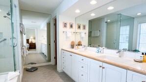 A modern bathroom with a large mirror, a glass shower enclosure, and a vanity with a sink. - JHRL - Pieper Garden Home 30 night rental (Wilson)