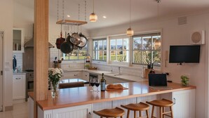 Una cocina moderna con una isla grande, ollas colgantes, una botella de vino y un televisor.
