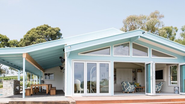 A modern house with a covered patio, large windows, and a garden view. - SOUMAH Wines (Gruyere)
