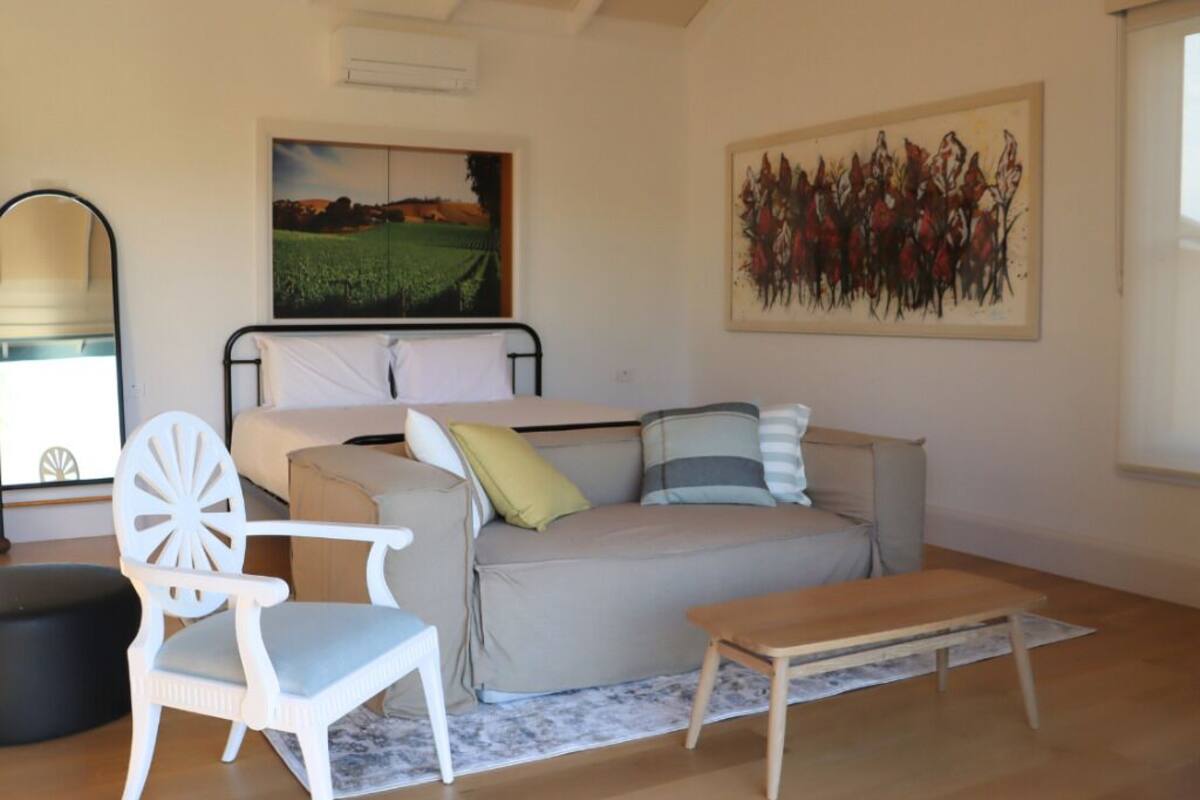 A cozy room with a bed, a sofa, a chair, and a wooden table.