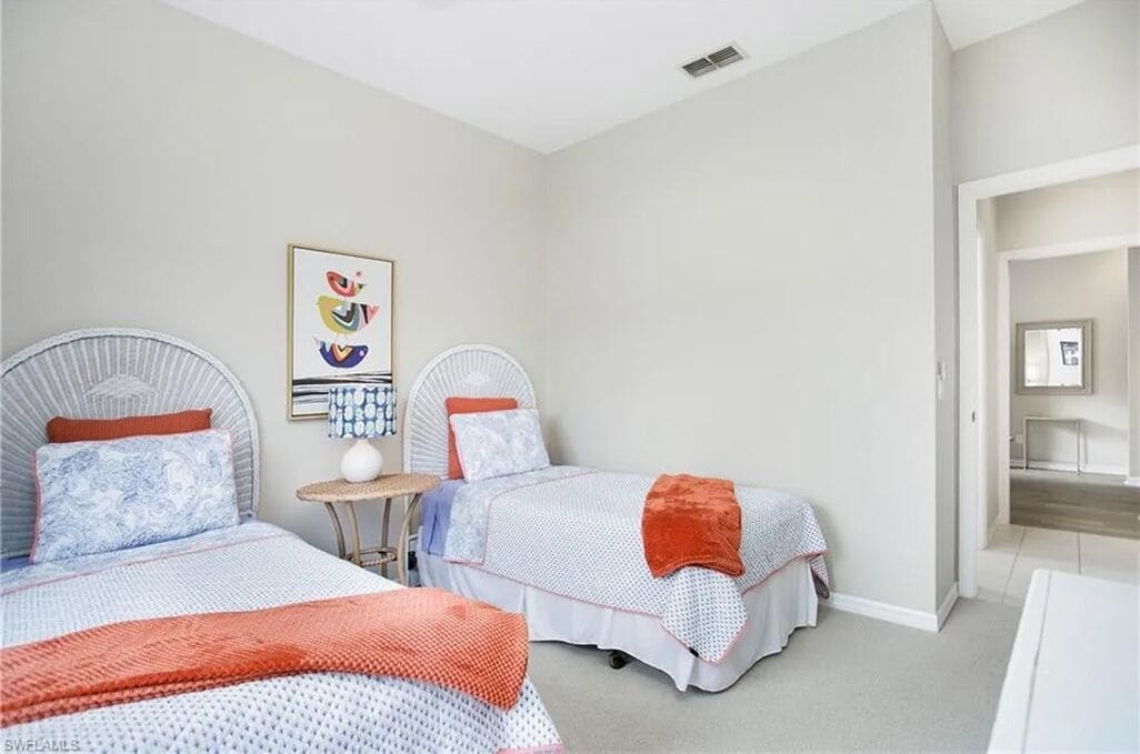 A bedroom with two beds, a small table, and a wall-mounted artwork.