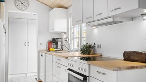 A modern kitchen with white cabinetry, a wooden countertop, a built-in oven, and a coffee maker. - Gorgeous home in Karrebæksminde (Karrebæksminde)