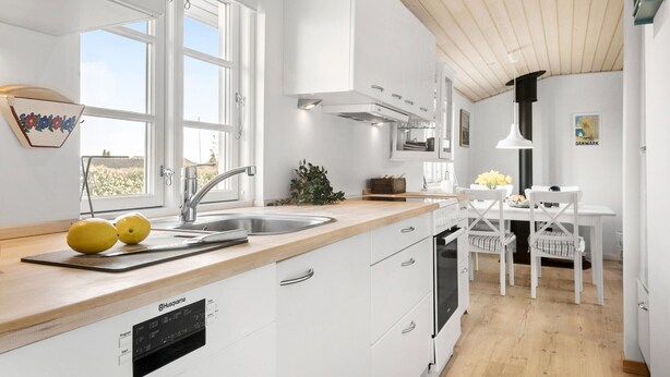 A modern kitchen with white cabinetry, a stainless steel sink, and a built-in dishwasher. - Gorgeous home in Karrebæksminde (Karrebæksminde)