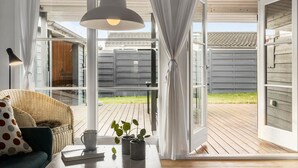 A cozy room with a wicker chair, a table with a book and a mug, and a hanging pendant light. - Gorgeous home in Karrebæksminde (Karrebæksminde)