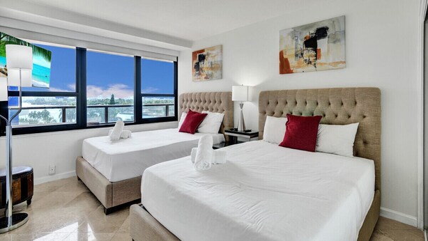 A hotel room with two beds, a large window with a view, and artwork on the walls. - Beach Resort condo /921 (Miami Beach)
