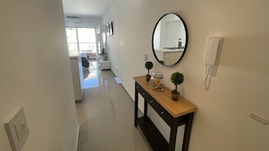 A hallway with a wooden console table, a round mirror, a telephone, and small potted plants. - San Telmo Oasis Contemporary Luxurious Studios Num6863 (Buenos Aires)