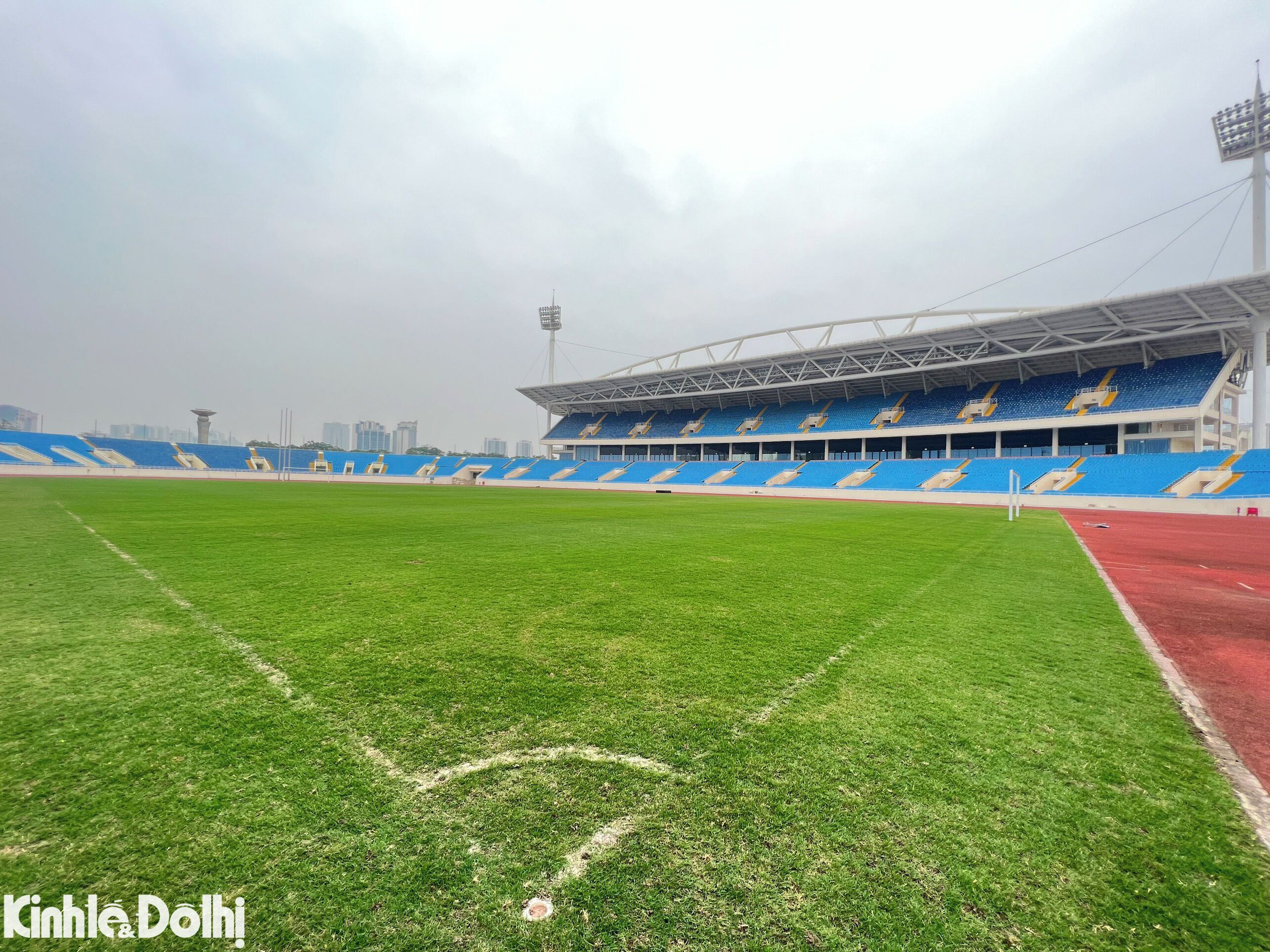 A stadium with blue and white seating, a green field, and a red track.