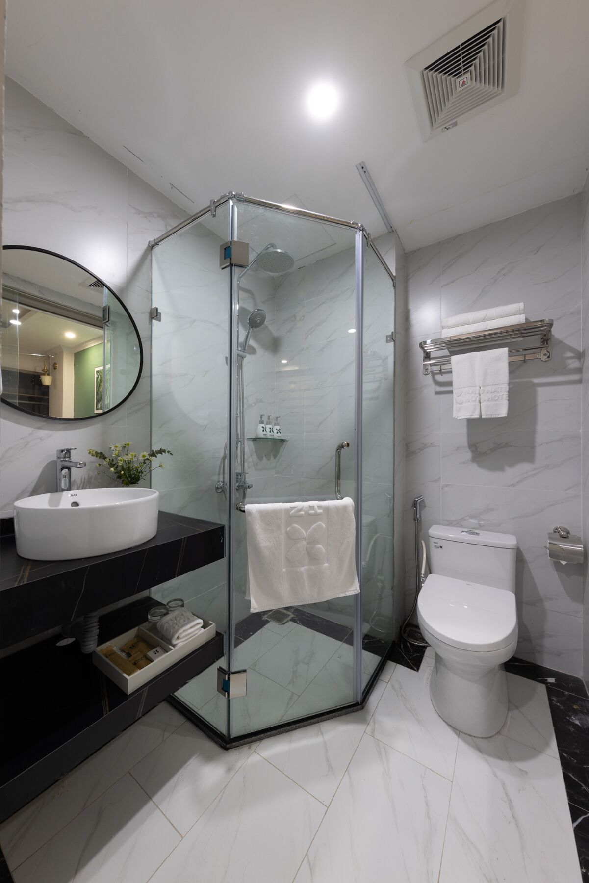 A modern bathroom with a glass-enclosed shower, a white sink, and a toilet.