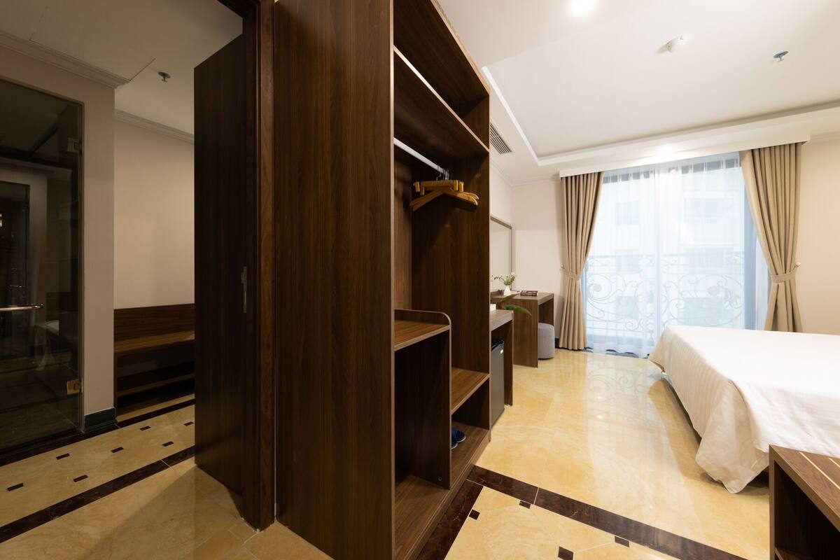 A hotel room with a bed, a wardrobe, a desk, and a bathroom.