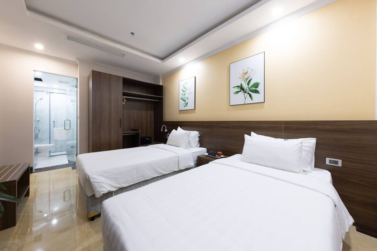 A hotel room with two beds, a walk-in closet, a shower, and a wall-mounted artwork.