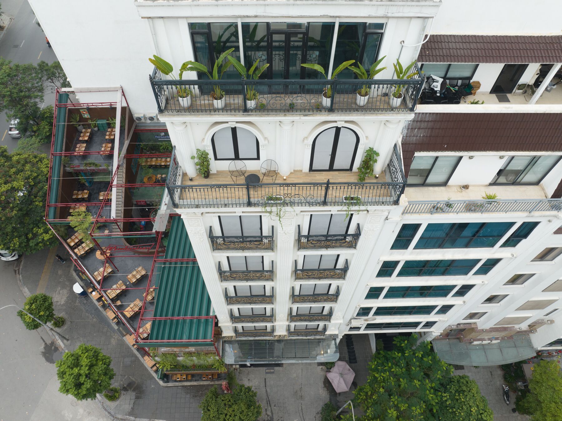 A multi-story building with balconies, outdoor seating, and potted plants.