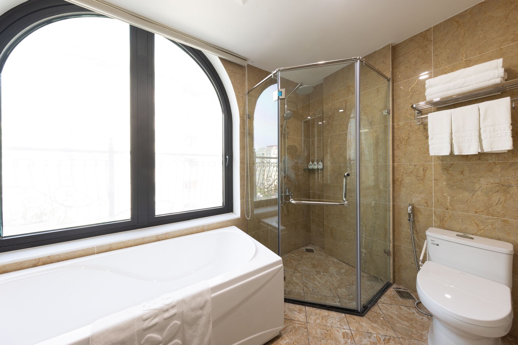 A bathroom with a bathtub, toilet, and glass-enclosed shower.