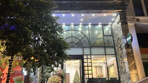 Entrada de hotel con una imponente escalera, fachada de vidrio y barandilla de metal decorativa.