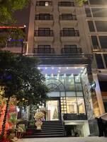 Entrada de hotel con una imponente escalera, fachada de vidrio y barandilla de metal decorativa.
