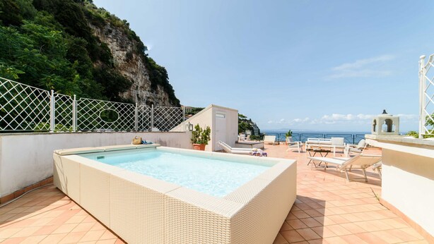 A rooftop pool with a view of the sea and a cliff.