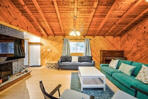 A cozy log cabin interior with a fireplace, a sofa, a green couch, and a dining table. - Jamtel Arden cottage - Kennebec Lake, Arden ON. (Arden)