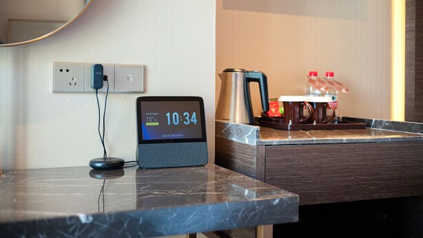 A hotel room with a digital clock displaying the time, a coffee maker, and a water bottle on the counter. - Zhangjiajie Metropolo Hotel (Zhangjiajie)