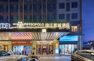 Entrada de un hotel con puerta giratoria, señalización iluminada y acceso visible al vestíbulo.