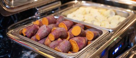 A buffet with various food items, including sweet potatoes and other dishes.