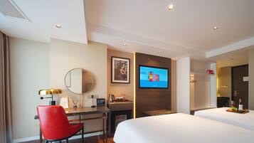 Habitación de hotel con cama, escritorio y silla, televisor montado en la pared y espejo.