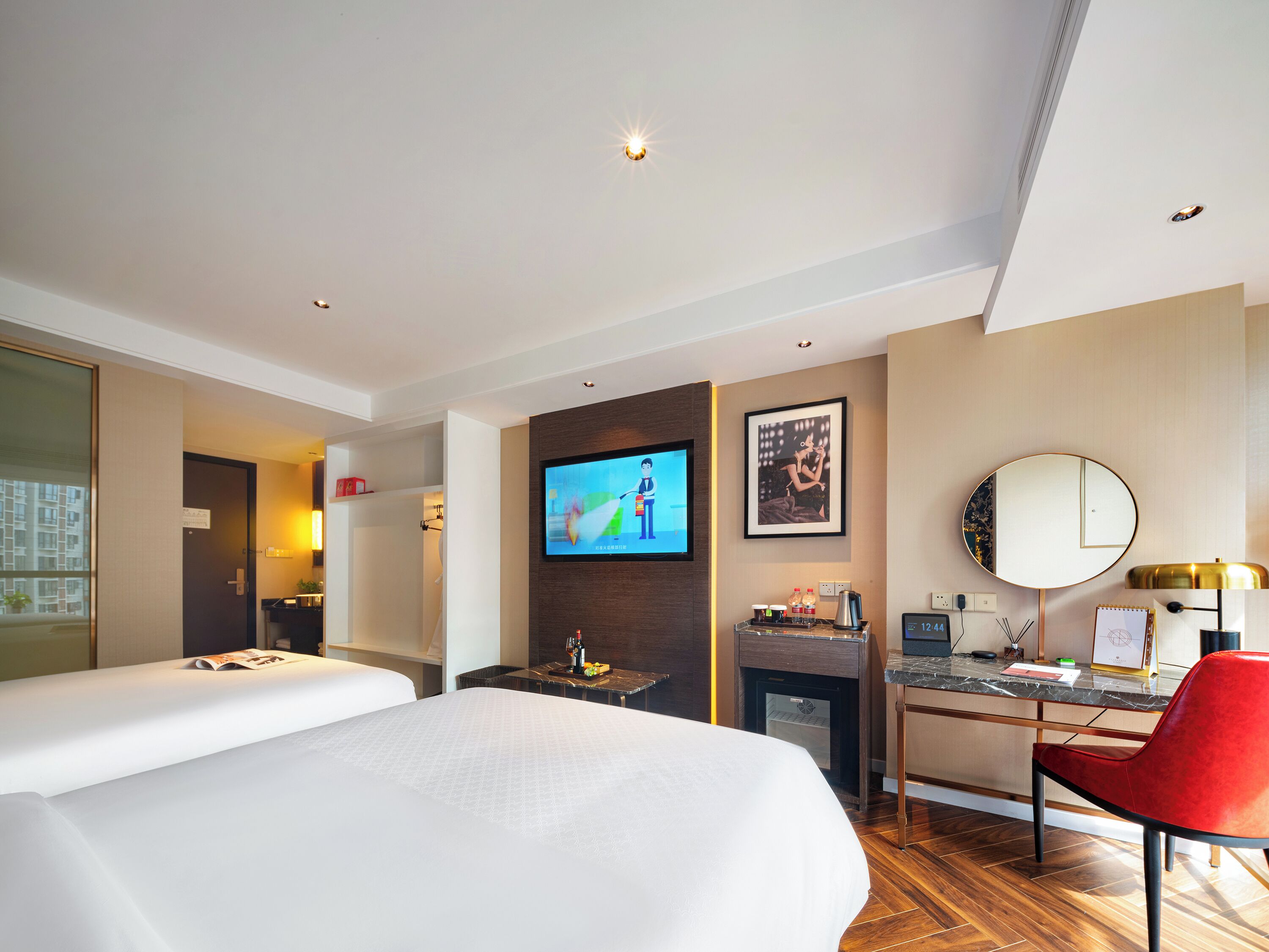 Une chambre d’hôtel comprenant un lit, un bureau avec une chaise, une télévision, une machine à café et un petit réfrigérateur.