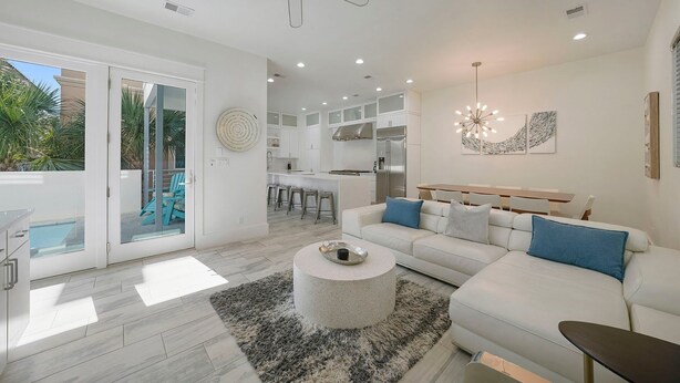 Un salón moderno con un sofá blanco, una mesa redonda de centro y una zona de comedor con mesa y sillas de madera.