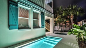 A residential building with a swimming pool, a balcony, and a staircase leading to the entrance.