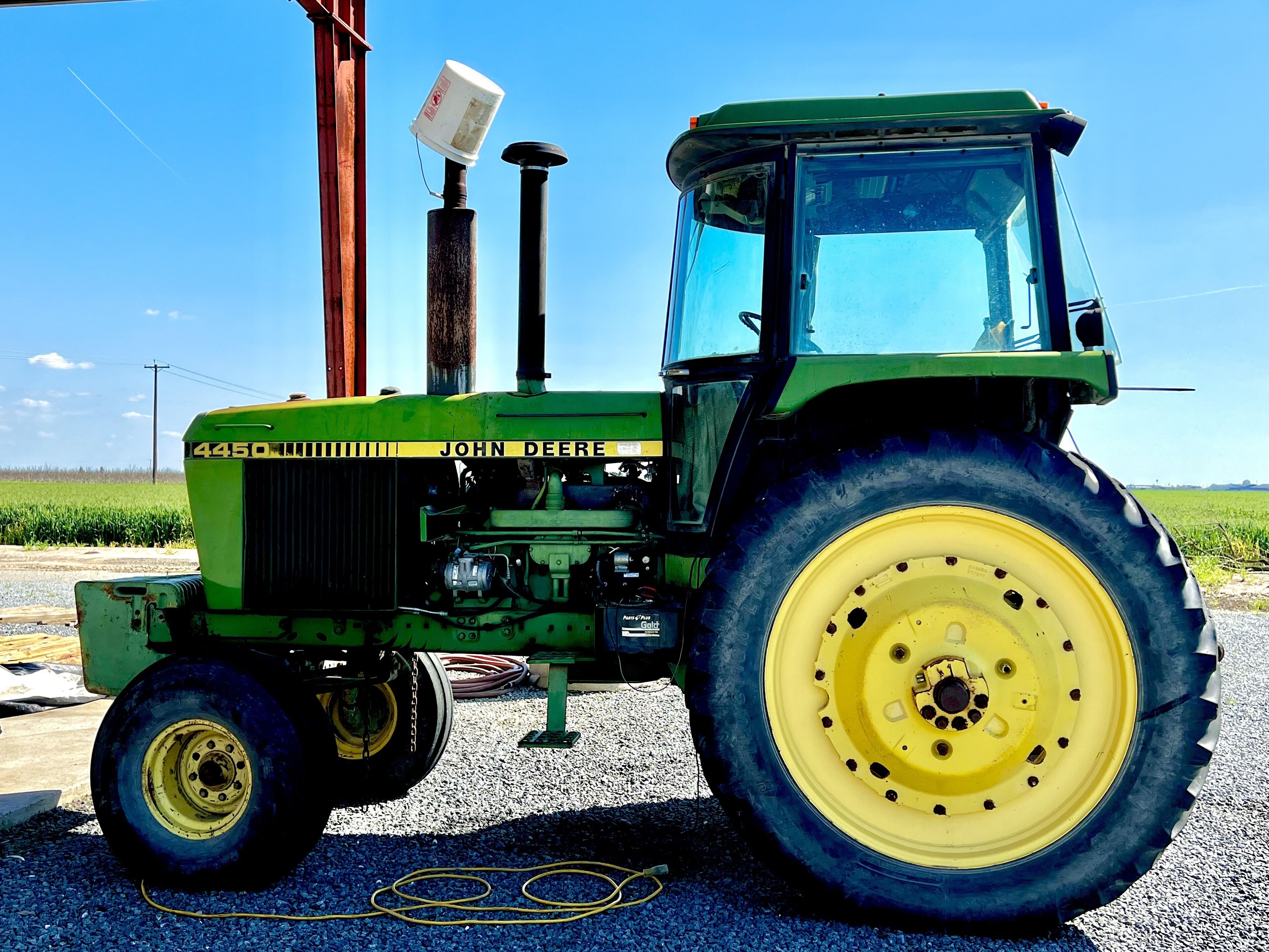 Un trattore verde John Deere dotato di grandi ruote gialle, una cabina e un faro montato sulla parte anteriore.