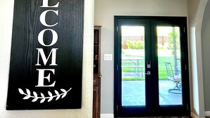 Un pasillo con un cartel que dice 'WELCOME', una puerta que da al exterior y una lámpara en el techo.