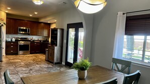 Una cocina moderna con electrodomésticos de acero inoxidable, armarios de madera y un comedor con mesa y sillas de madera.