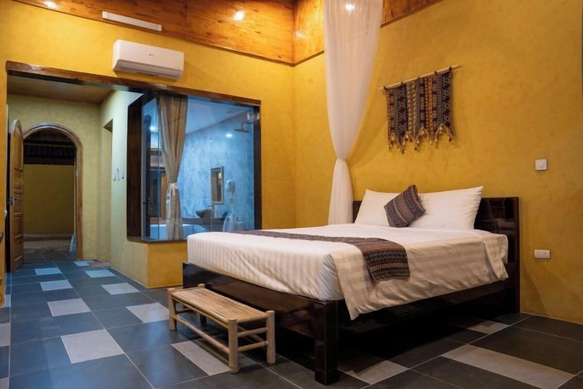 A bedroom with a bed, bench, and a mirror.