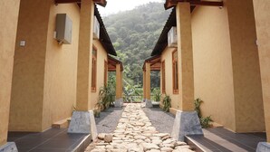 A corridor with a stone pathway leading to a view of a forested hill. - Sky Bay Lodge (Ha Giang 1)