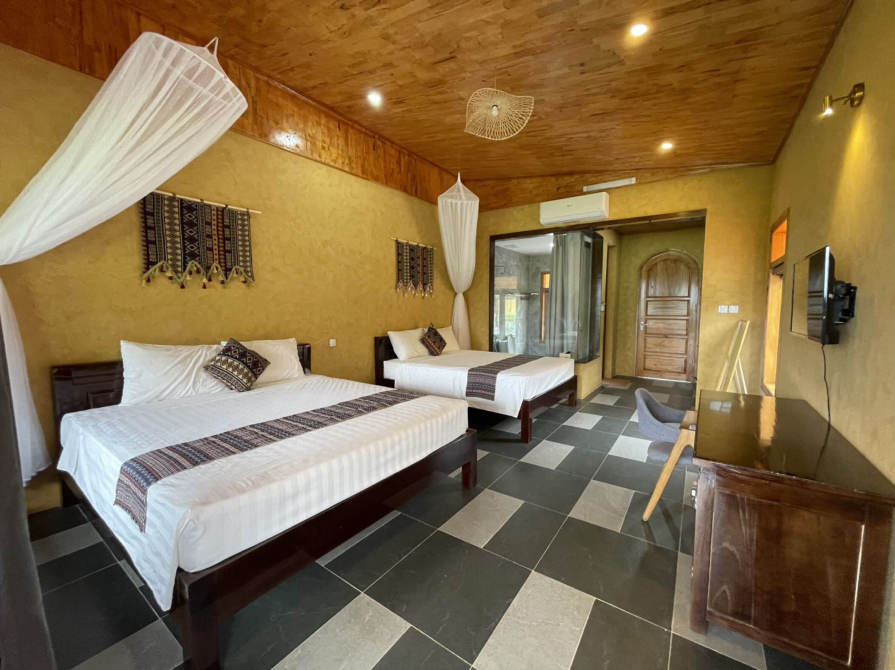 Een hotelkamer met twee bedden, een houten plafond en een geruit vloerkleed.