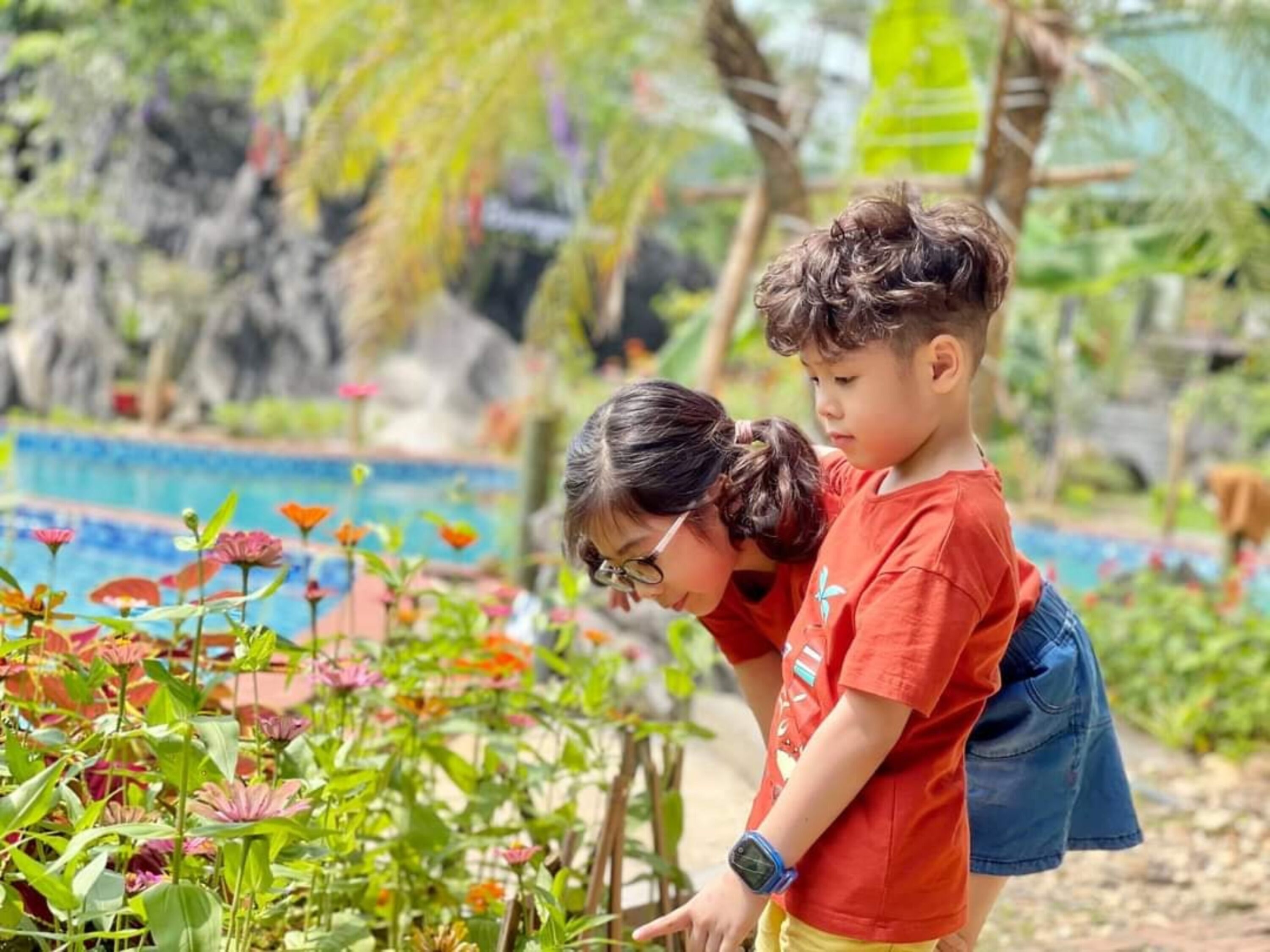 Un enfant et un adulte dans un jardin, avec une piscine en arrière-plan.