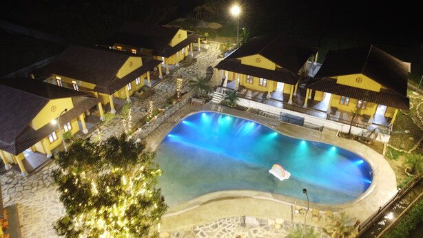 A resort with a swimming pool, multiple yellow-roofed buildings, and a stone pathway. - Sky Bay Lodge (Ha Giang 1)