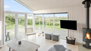 Una sala de estar moderna con televisor grande, chimenea y vistas al exterior.