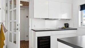 Cozinha moderna com armários brancos, lava-louças preta e bancada.