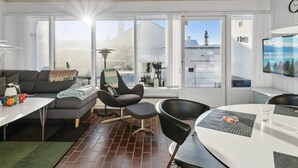 Uma sala de estar moderna com sofá, cadeiras, mesa de jantar e janelas amplas.