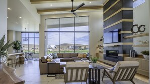 A spacious living room with a large window, a fireplace, and a modern design.