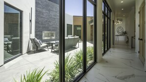 A modern interior with large windows, a hallway, and a patio area with outdoor furniture.