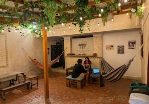 A cozy indoor space with a hammock, wooden benches, and a rustic brick floor. - Paisa Hostel Medellín (Medellín)