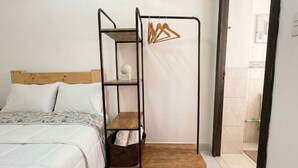 A bed with a wooden headboard, a metal bunk bed with a wooden platform, and a hanging clothes rack.