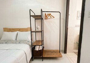 A bed with a wooden headboard, a metal bunk bed with a wooden platform, and a hanging clothes rack. - Paisa Hostel Medellín (Medellín)