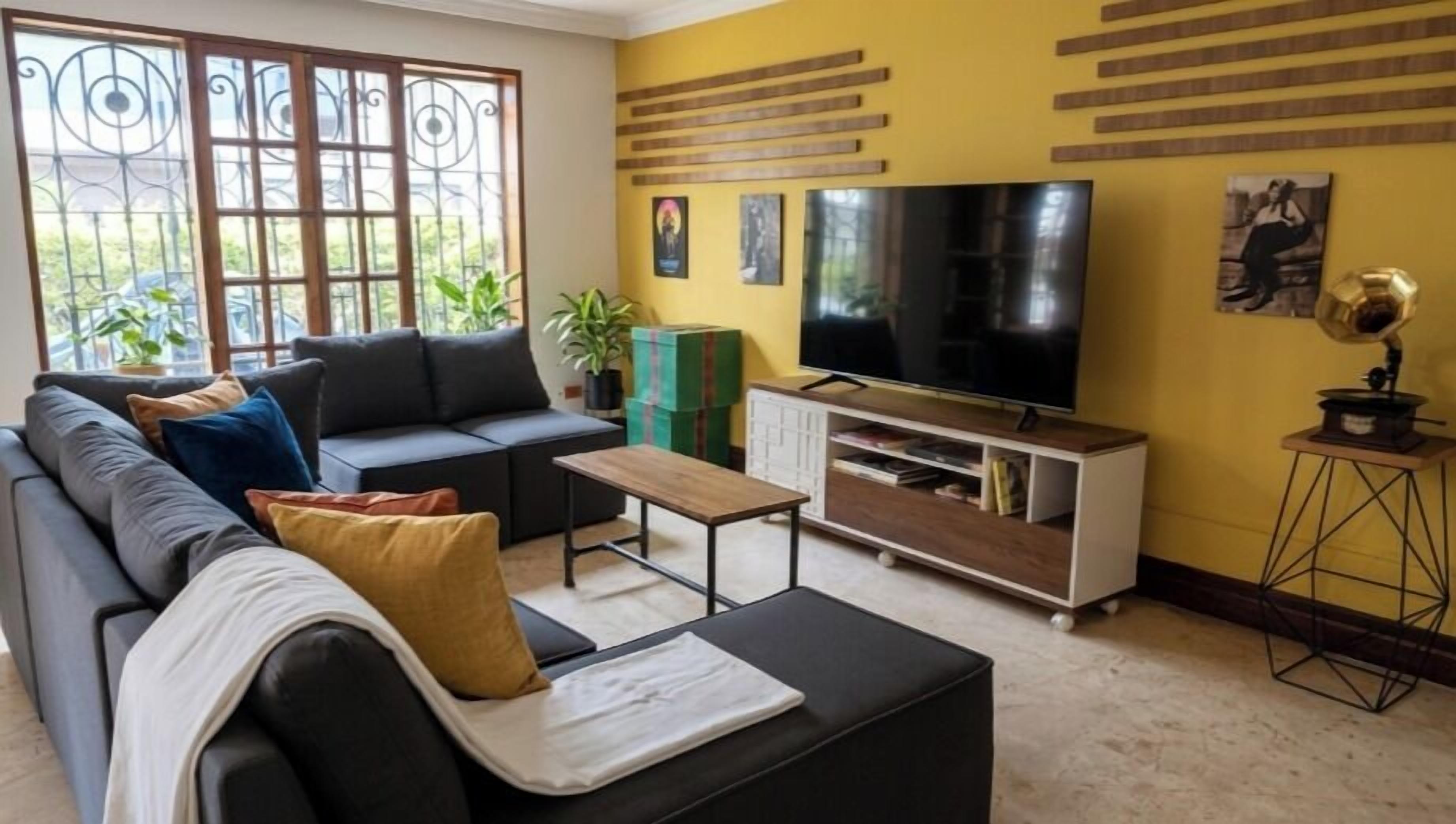 A living room with a sofa, a coffee table, a TV, and a bookshelf.