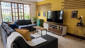 A living room with a sofa, a coffee table, a TV, and a bookshelf.