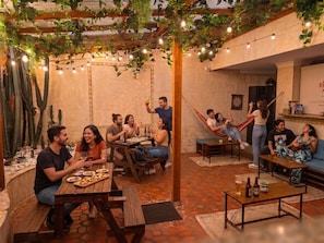 A cozy outdoor seating area with tables, chairs, and a hammock. - Paisa Hostel Medellín (Medellín)