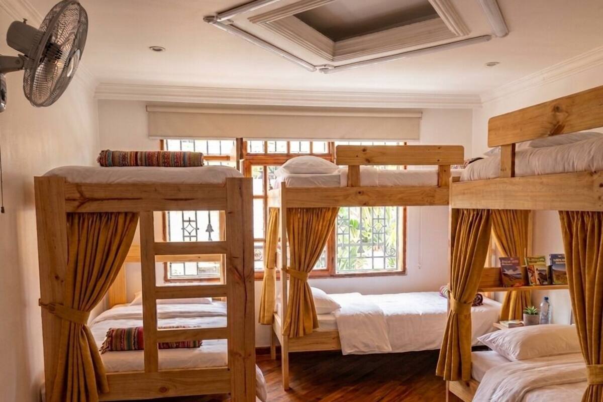 Una habitación con literas, ventilador de techo y ventana con cortinas.