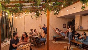 An indoor social gathering with people seated at tables, a hammock, and a casual seating area.
